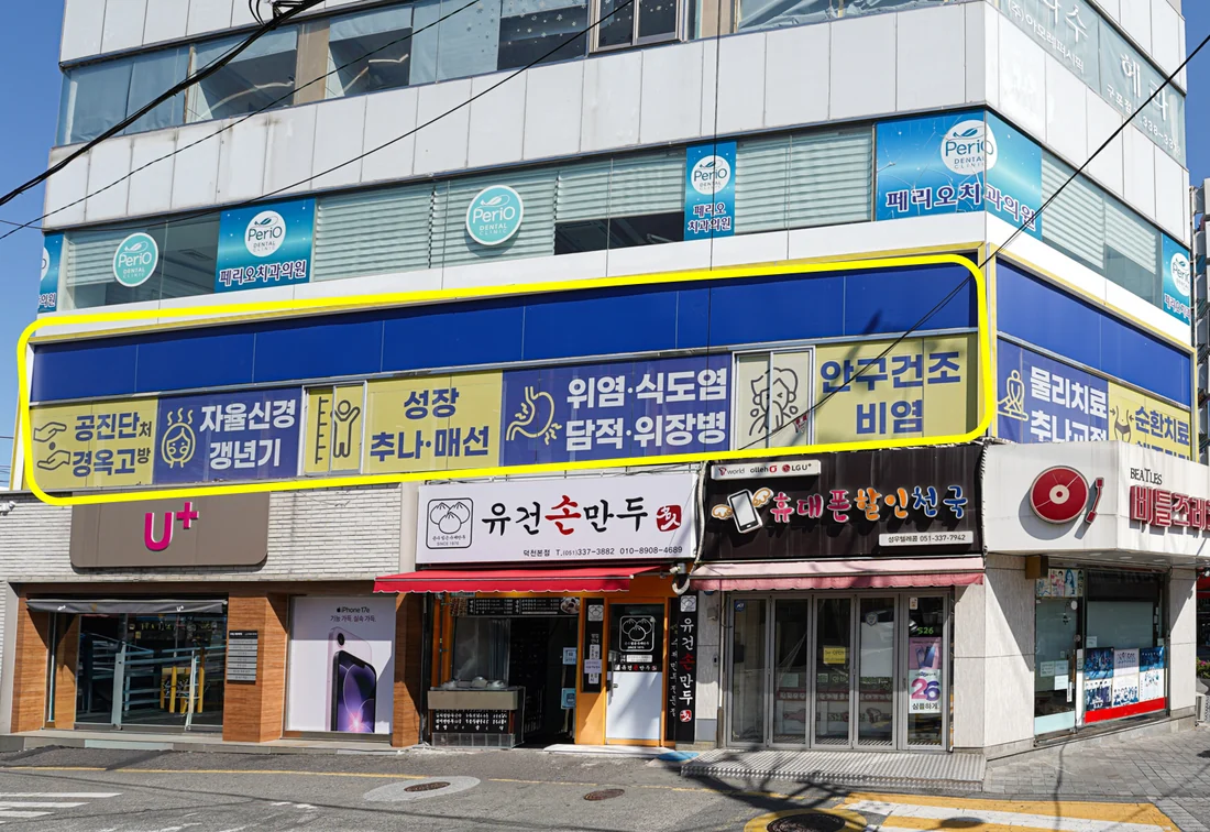 건물 외관 — 2층 파란 간판에 공진단·자율신경·성장·추나·위염·암수술 후 관리가 적혀 있다